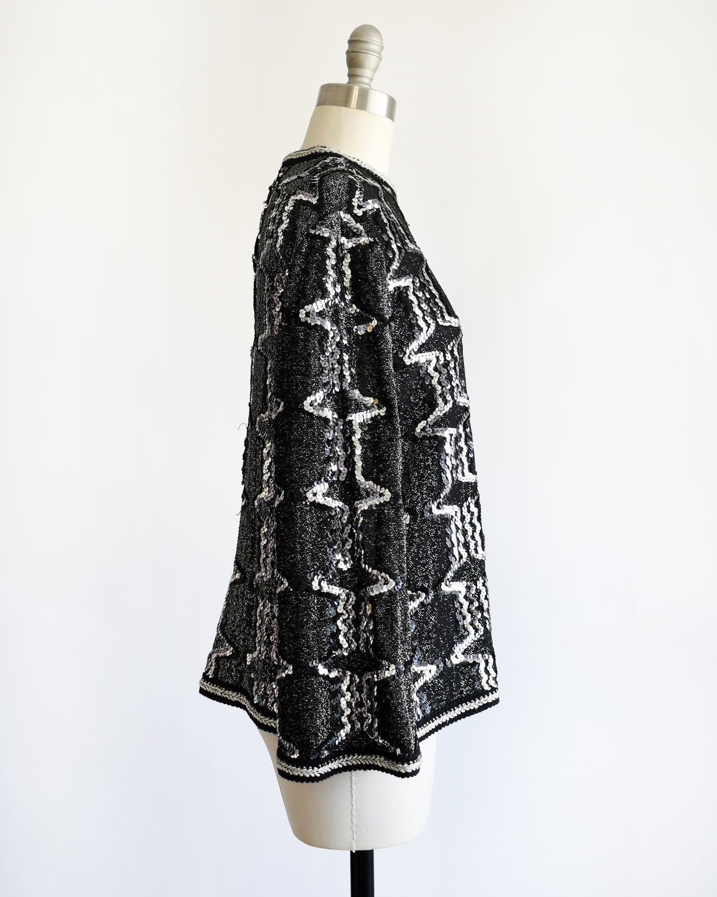 side view of a vintage 1970s/1980s Black and silver sequin top on a mannequin against a white background