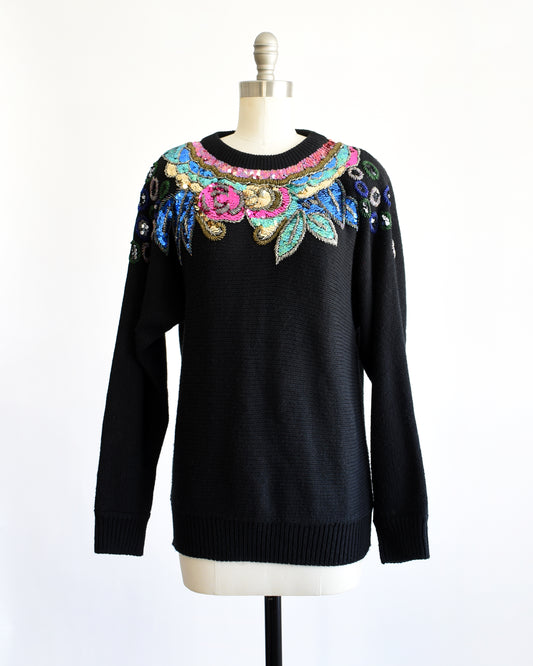 a vintage 1980s black sweater with colorful floral sequin and beaded detail on a mannequin against a white background