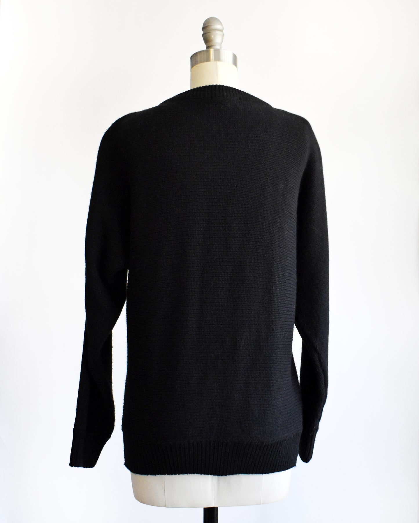 back view of a vintage 1980s black sweater on a mannequin against a white background