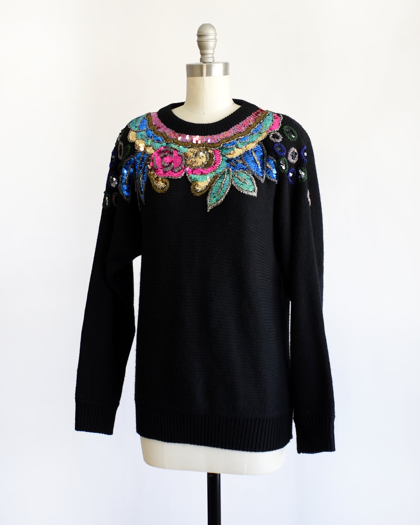 side view of a vintage 1980s black sweater with colorful floral sequin and beaded detail on a mannequin against a white background