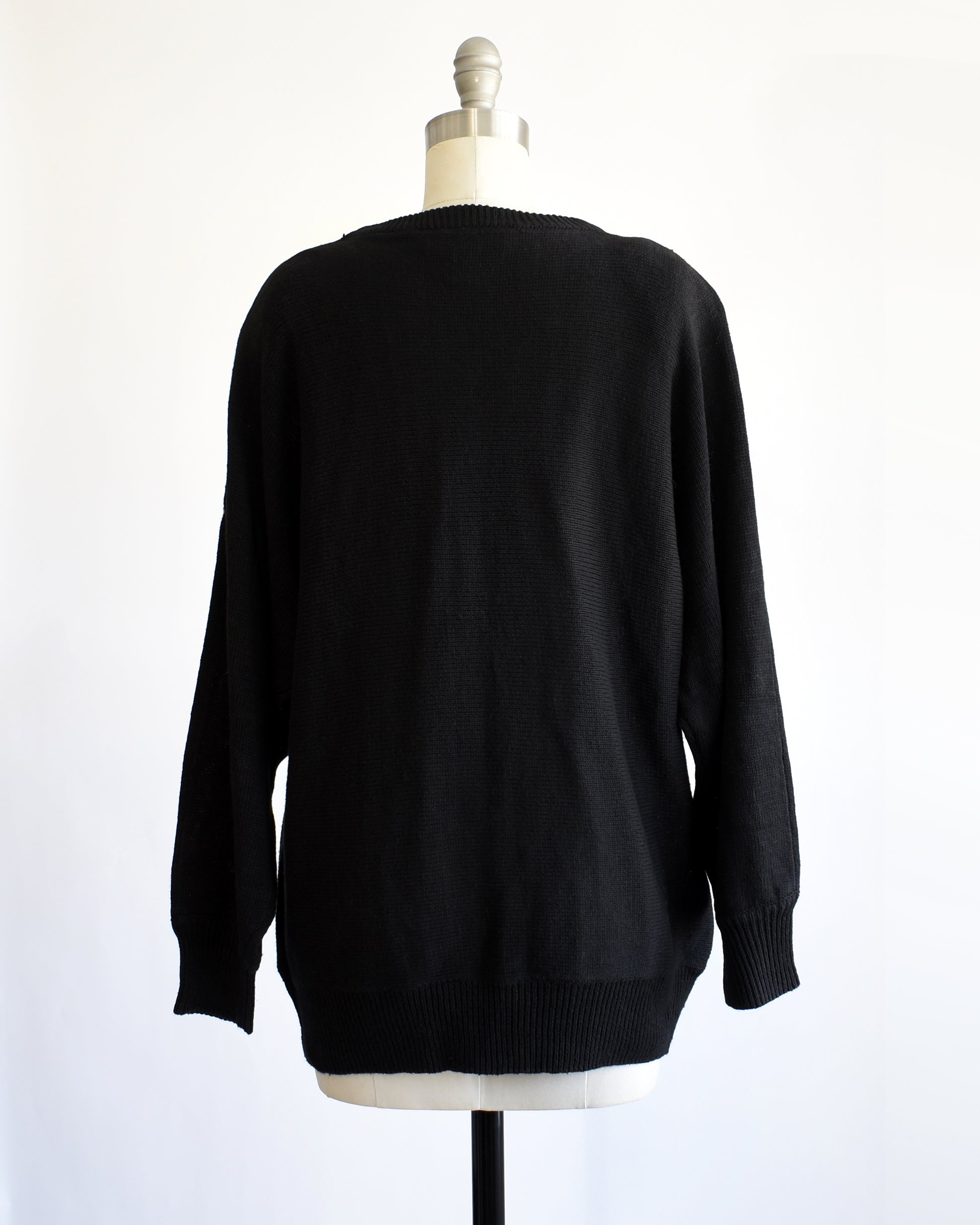 back view of a vintage black sweater with colorful gemstone sequins and tassel details on a mannequin against a white background