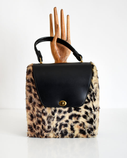 a vintage 1950s faux leopard print purse with a wooden hand in the background