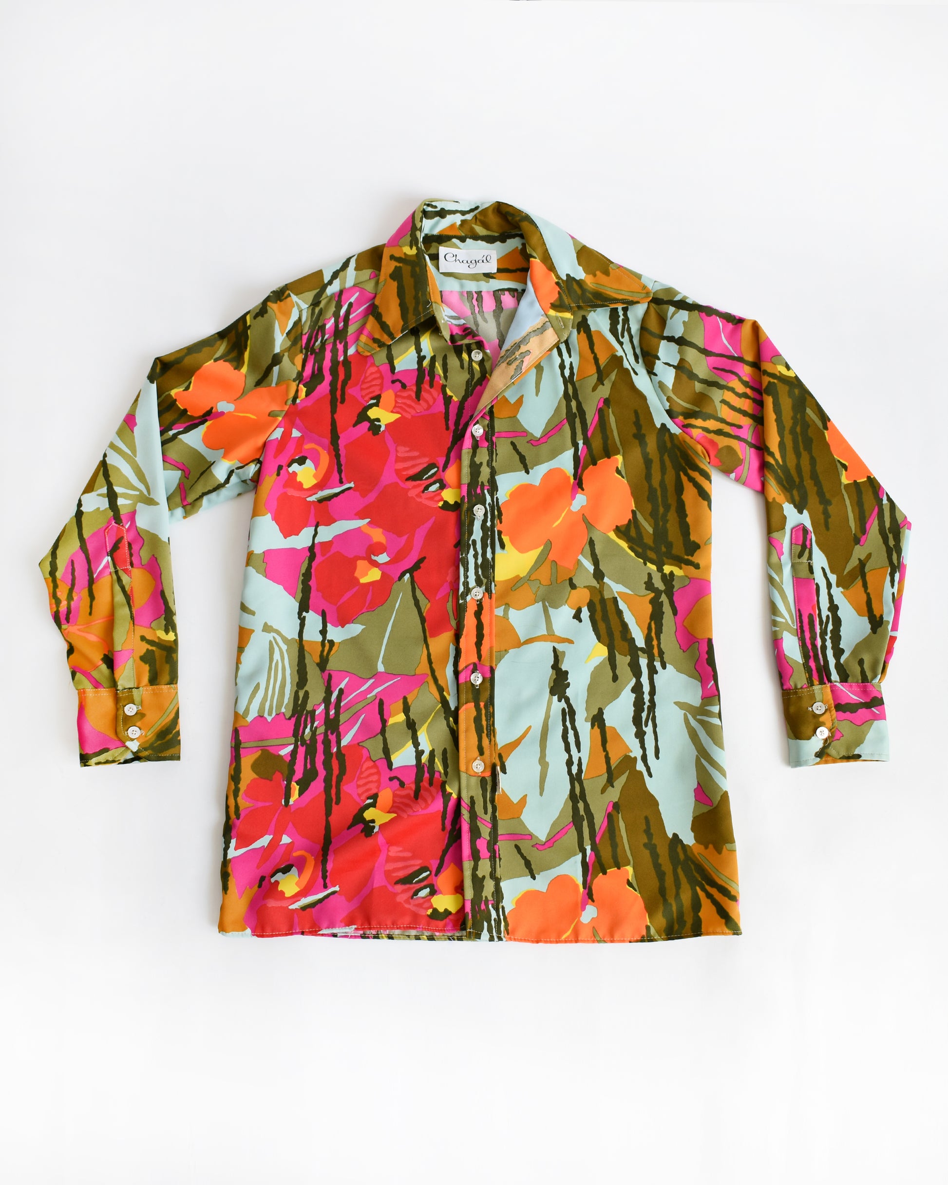 A long-sleeve vintage 1970s button-up shirt with a vibrant, multicolor tropical floral print, laid flat against a plain white background.