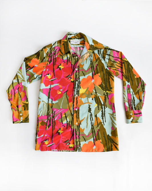A long-sleeve vintage 1970s button-up shirt with a vibrant, multicolor tropical floral print, laid flat against a plain white background.