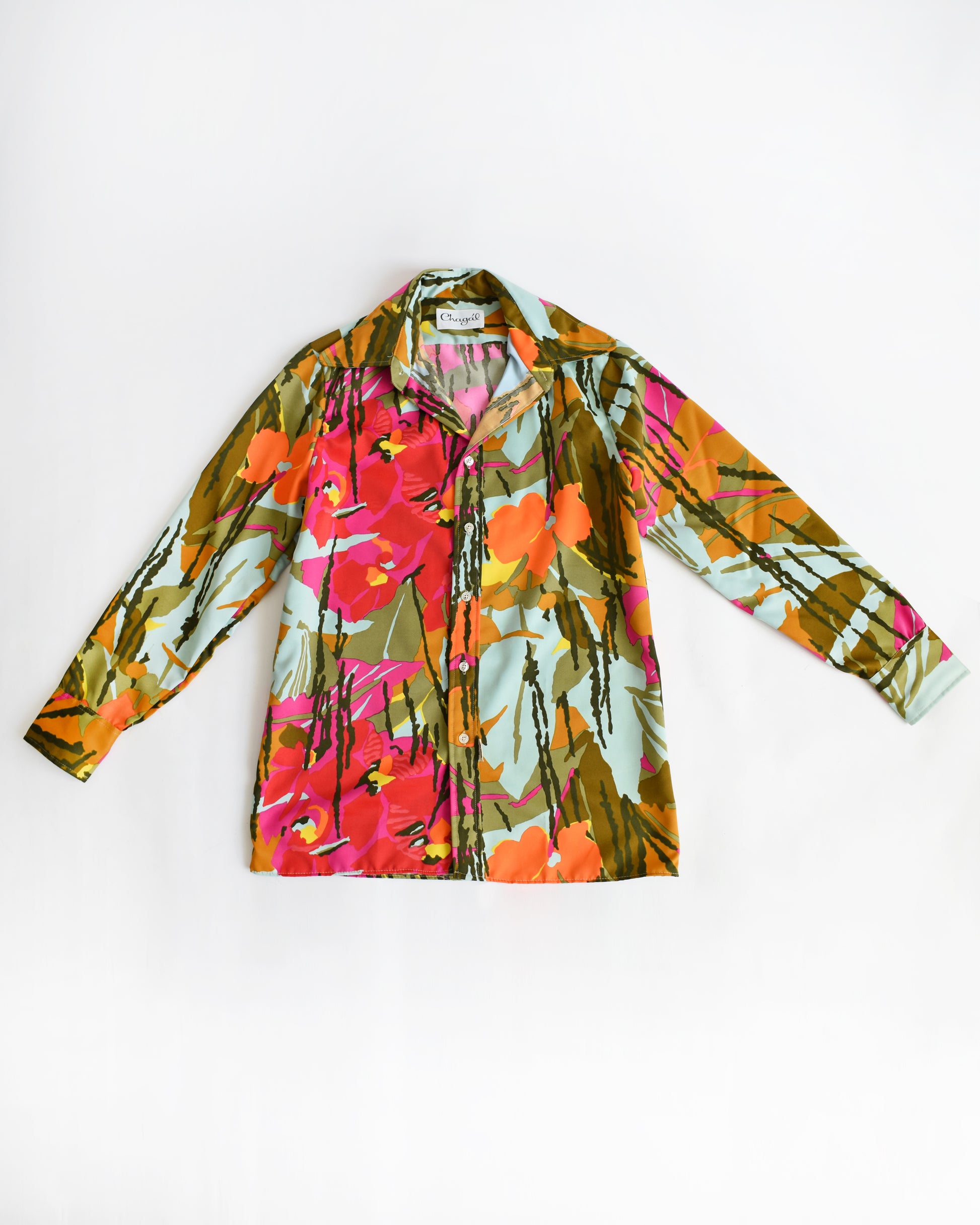A long-sleeve vintage 1970s button-up shirt with a vibrant, multicolor tropical floral print, laid flat against a plain white background.
