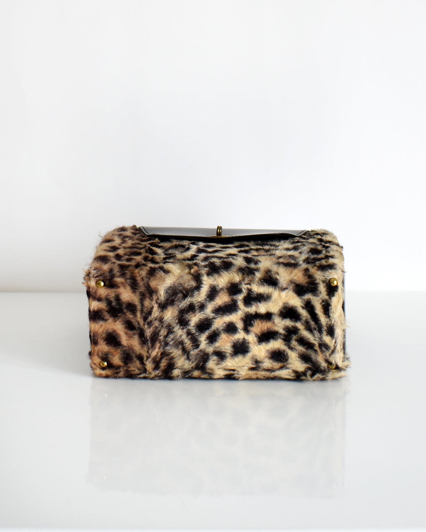 underside view of a vintage 1950s faux leopard print purse which shows the gold tone feet