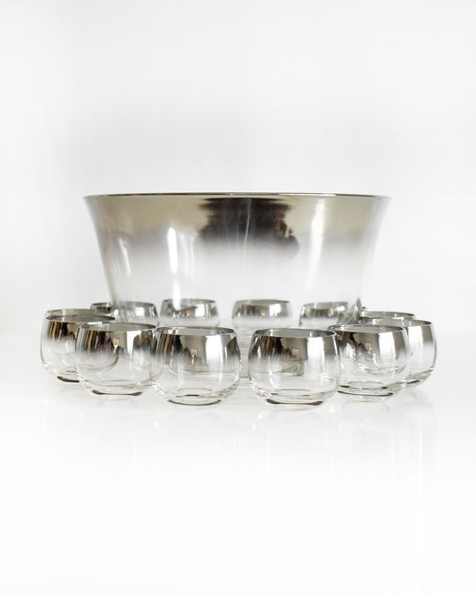 a vintage 1960s silver punch bowl and glasses set on a white background