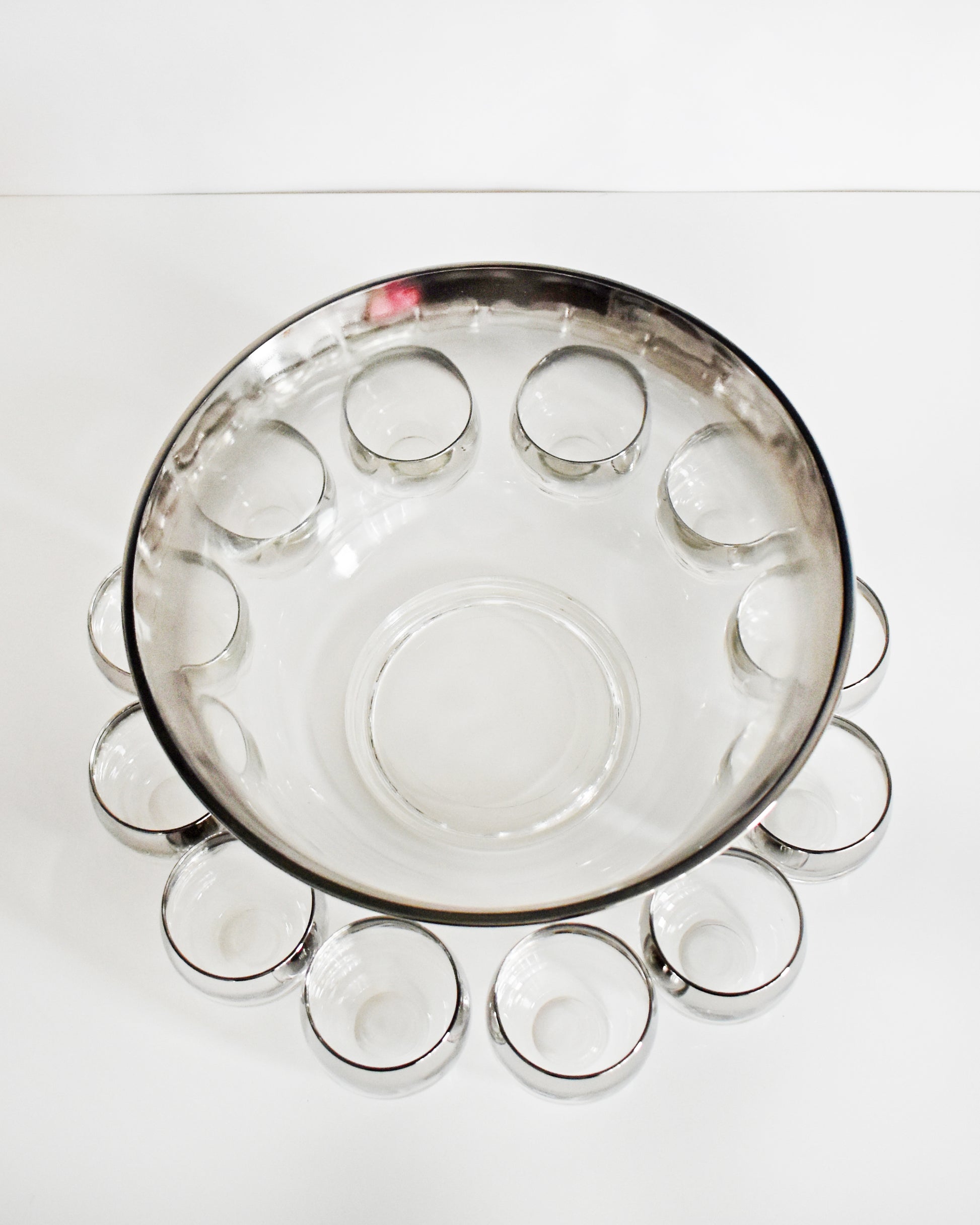 overhead shot of a vintage 1960s silver punch bowl and glasses set on a white background