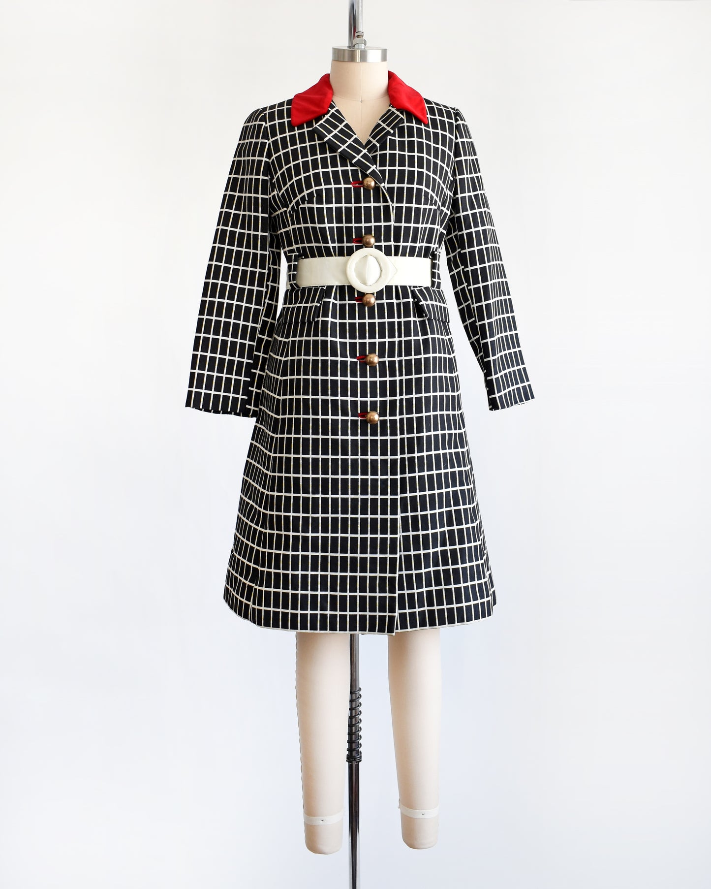 A vintage 70s black and white plaid mod coat with red velvet collar and wide white belt.