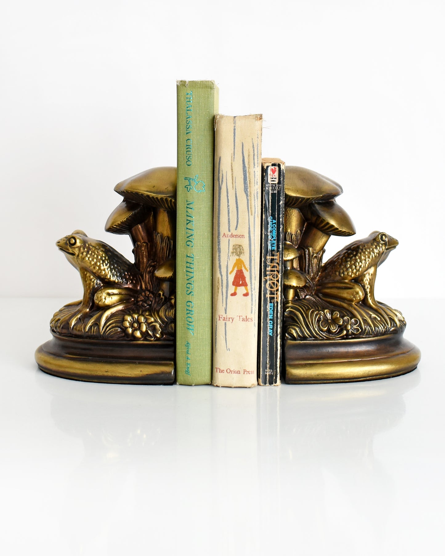  vintage brass frog and mushroom bookends with three books in the middle