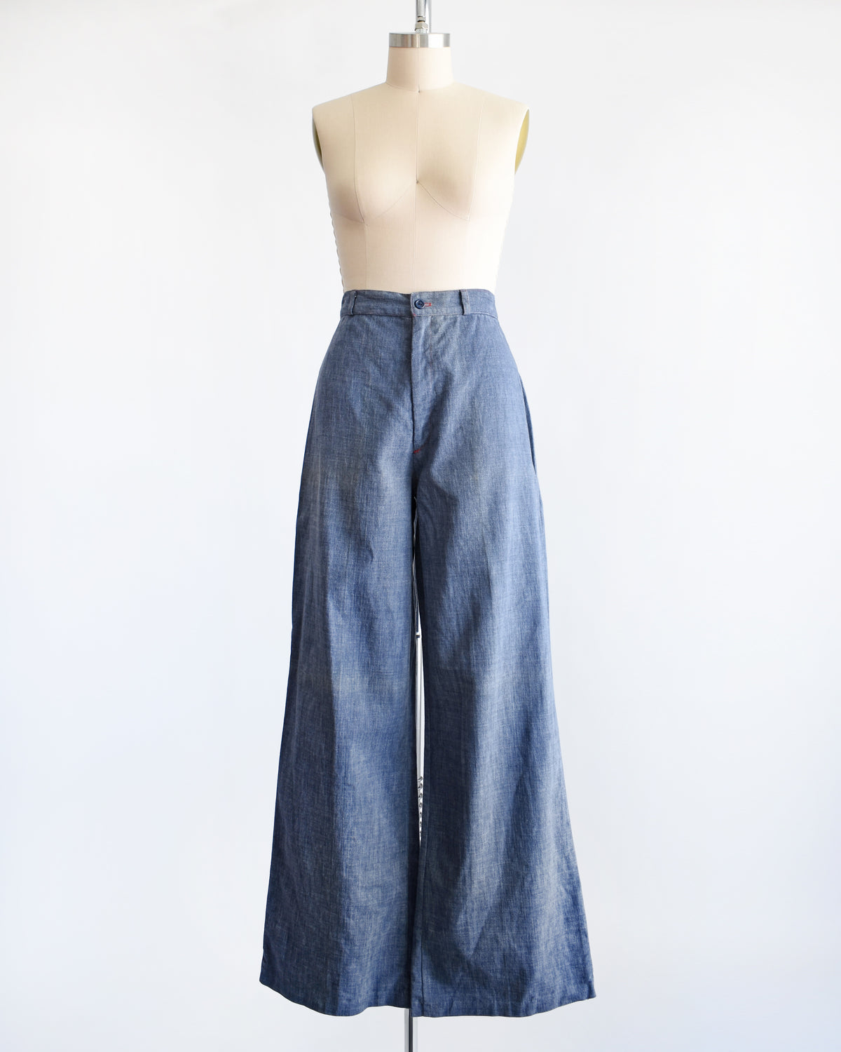 A pair of wide-leg vintage 1970s denim pants displayed on a cream dress form mannequin against a plain white background.