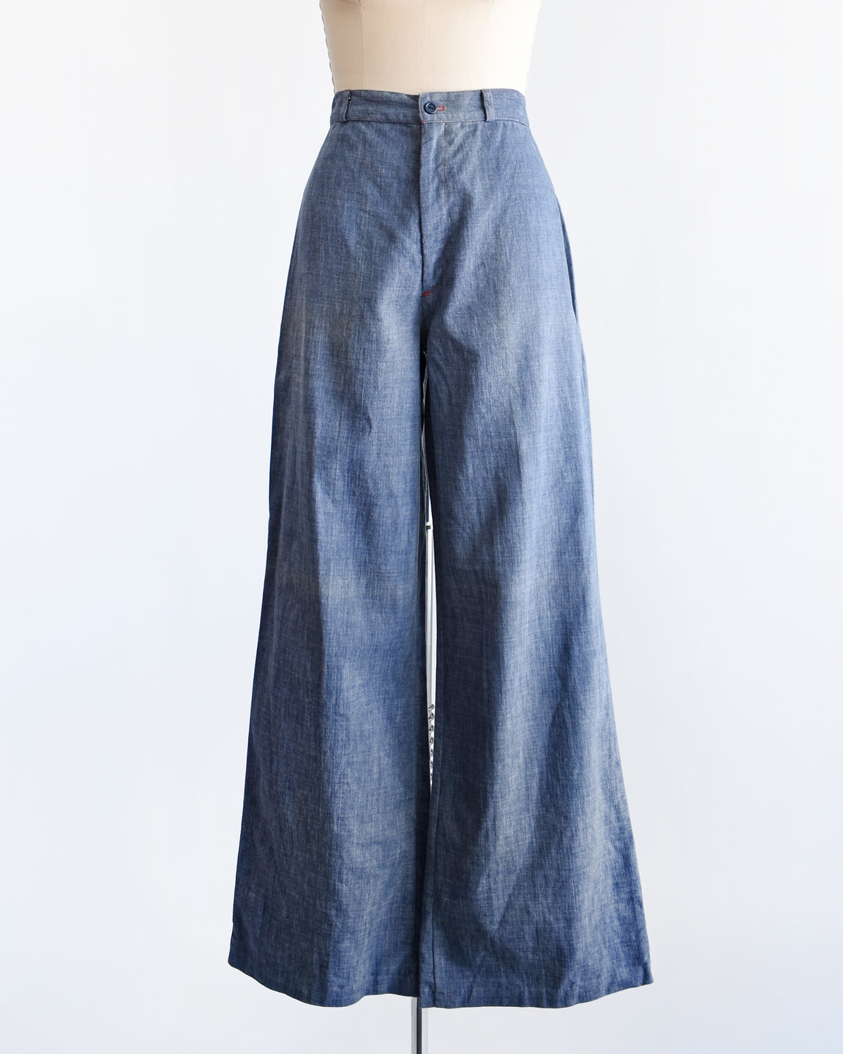 A pair of wide-leg vintage 1970s denim pants displayed on a cream dress form mannequin against a plain white background.