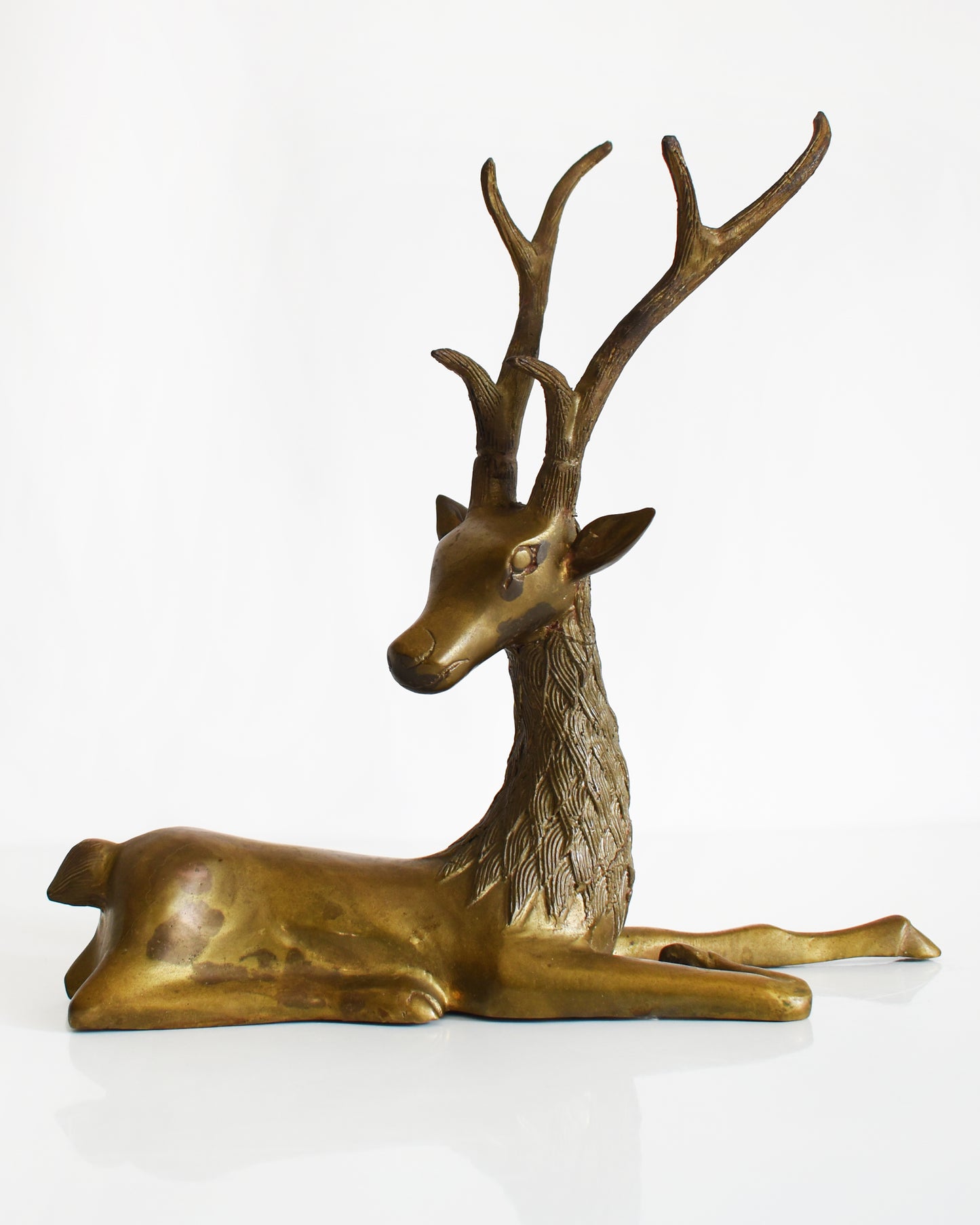 a vintage brass deer figurine on a white background