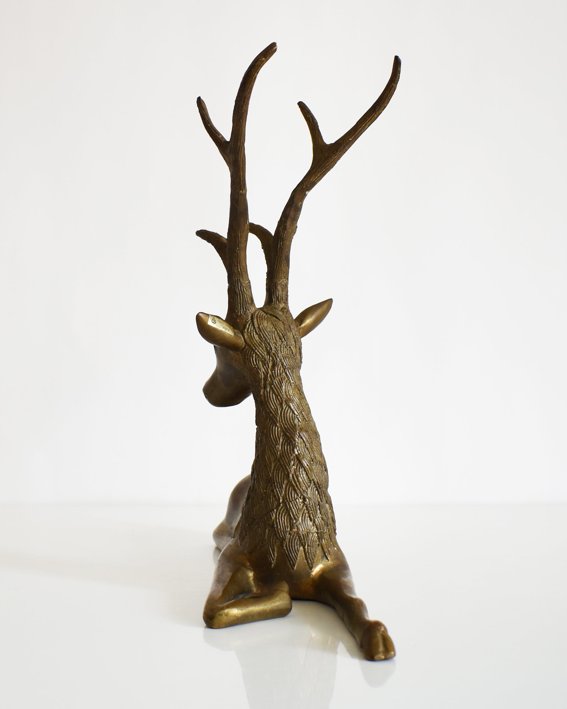back view of a vintage brass deer figurine on a white background