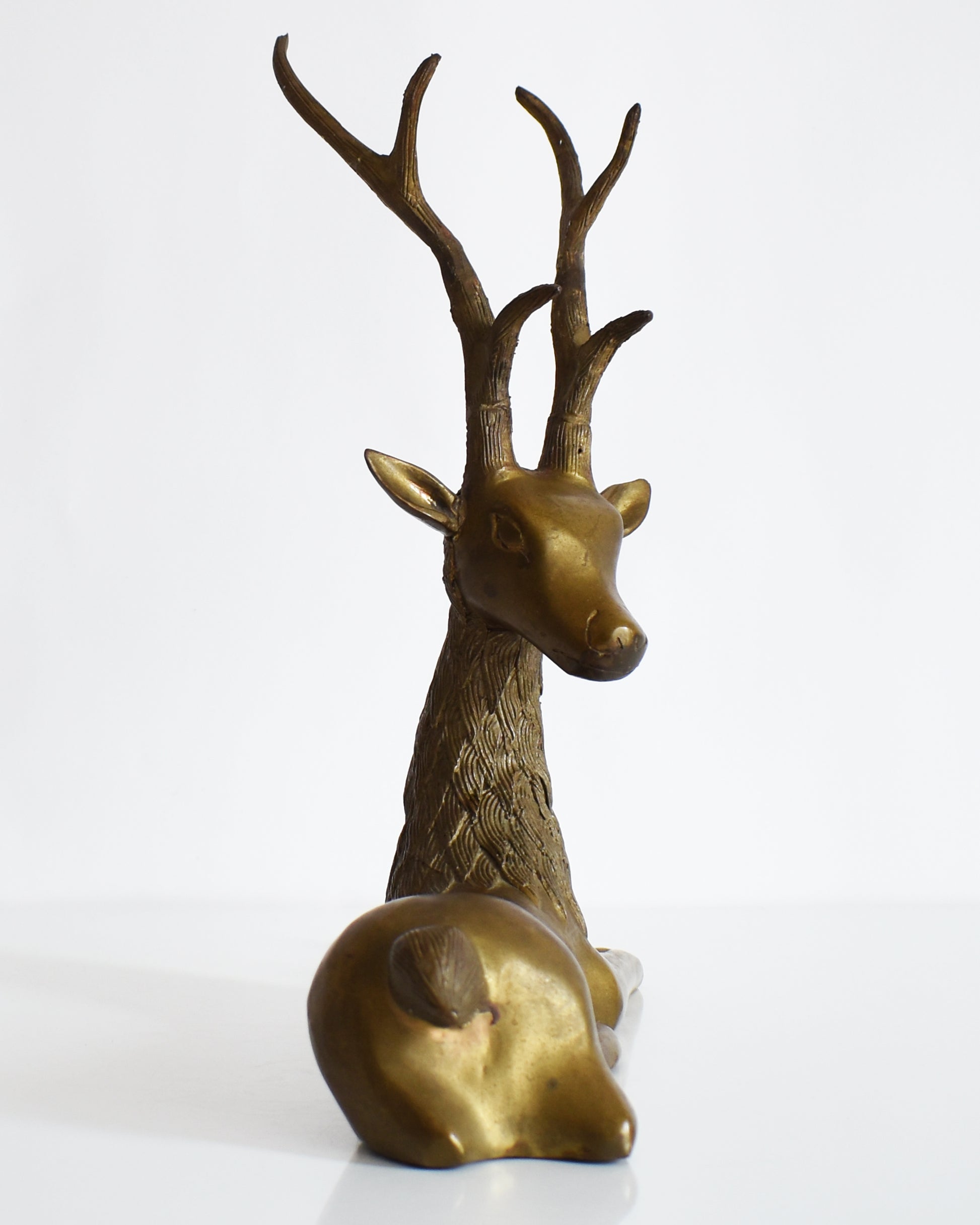 back view of a vintage brass deer figurine on a white background