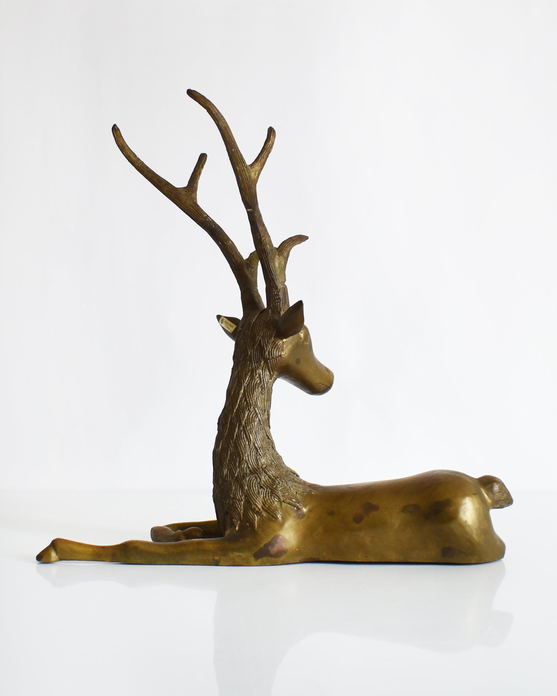back view of a vintage brass deer figurine on a white background