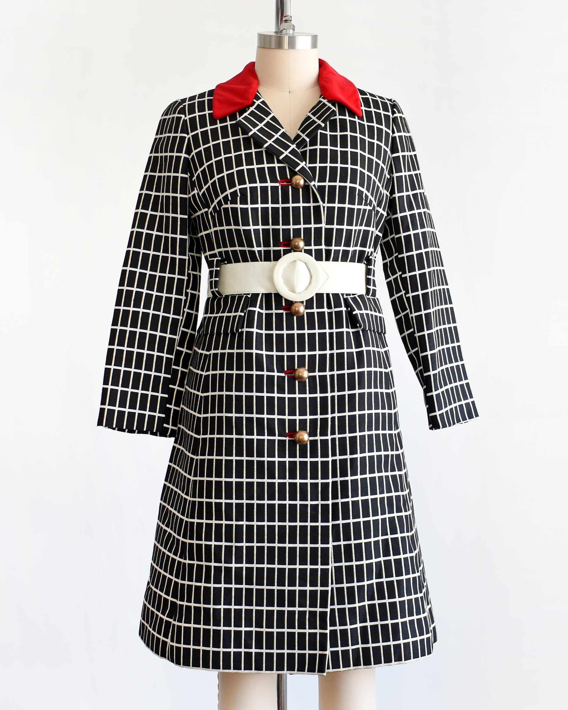 A vintage 70s black and white plaid mod coat with red velvet collar and wide white belt.