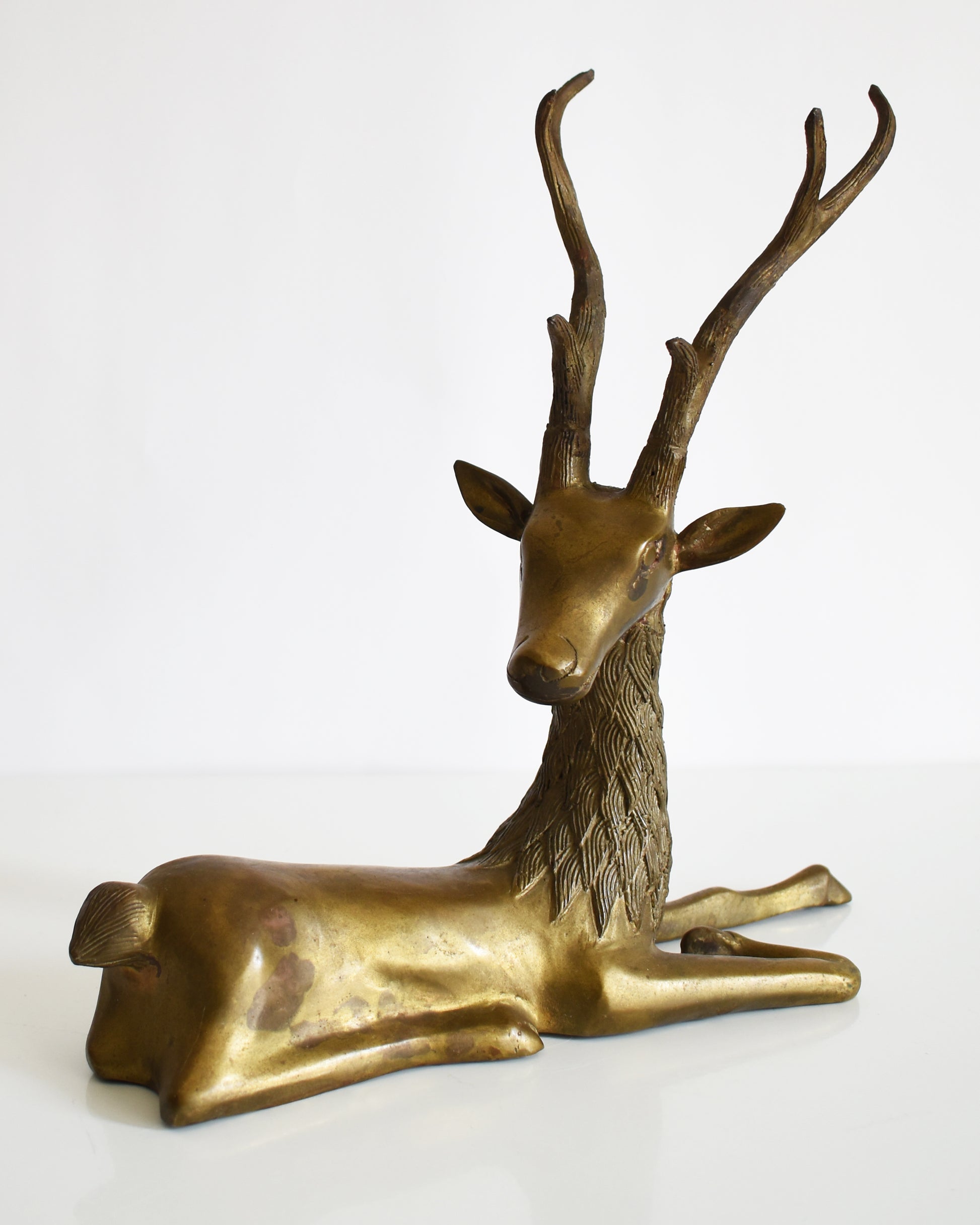 side front view of a vintage brass deer figurine on a white background