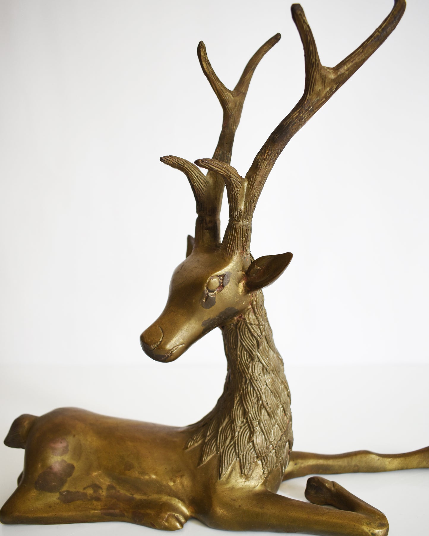 close up of a vintage brass deer figurine on a white background