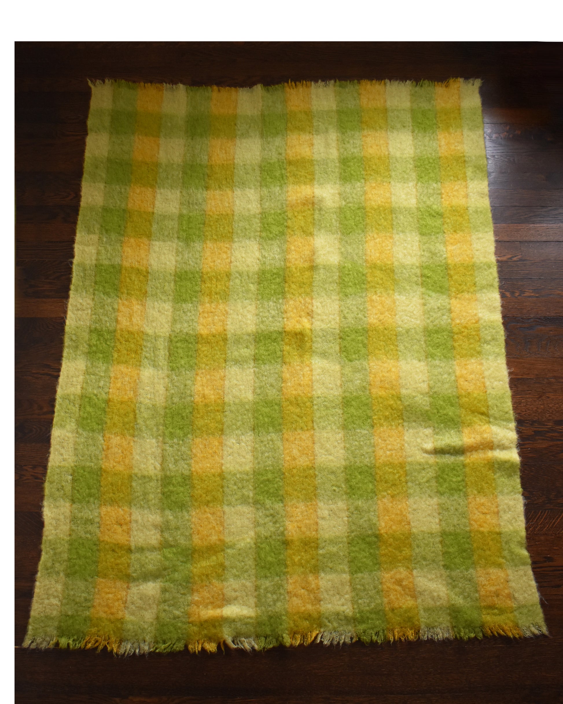 a vintage yellow and green plaid mohair wool blanket on a wood floor