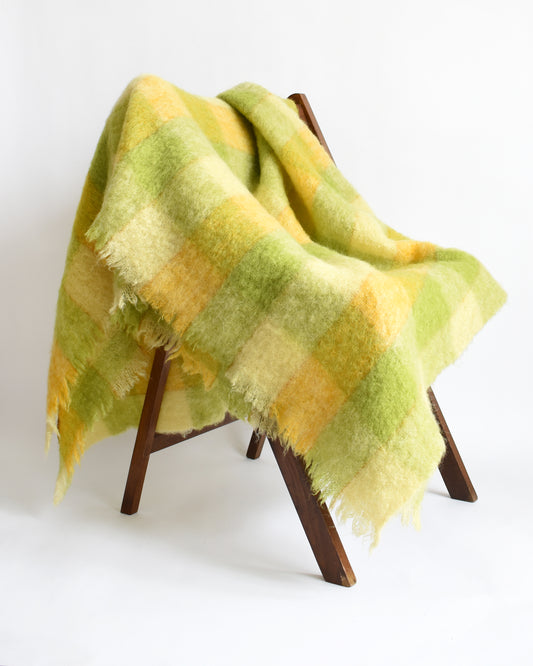 a vintage yellow and green plaid mohair wool blanket draped on a chair