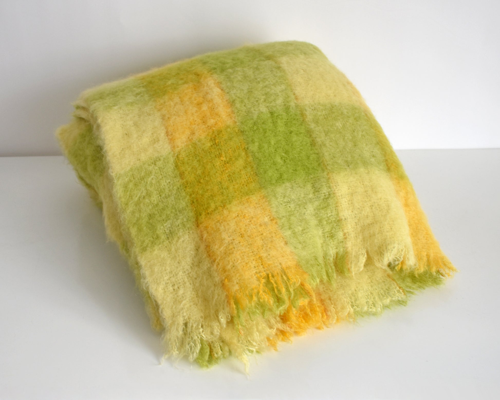 a vintage yellow and green plaid mohair wool blanket folded on a white table