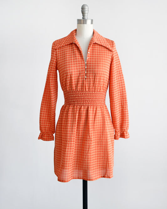 A vintage late 1960s early 1970s orange long sleeve mod mini dress with button front. 