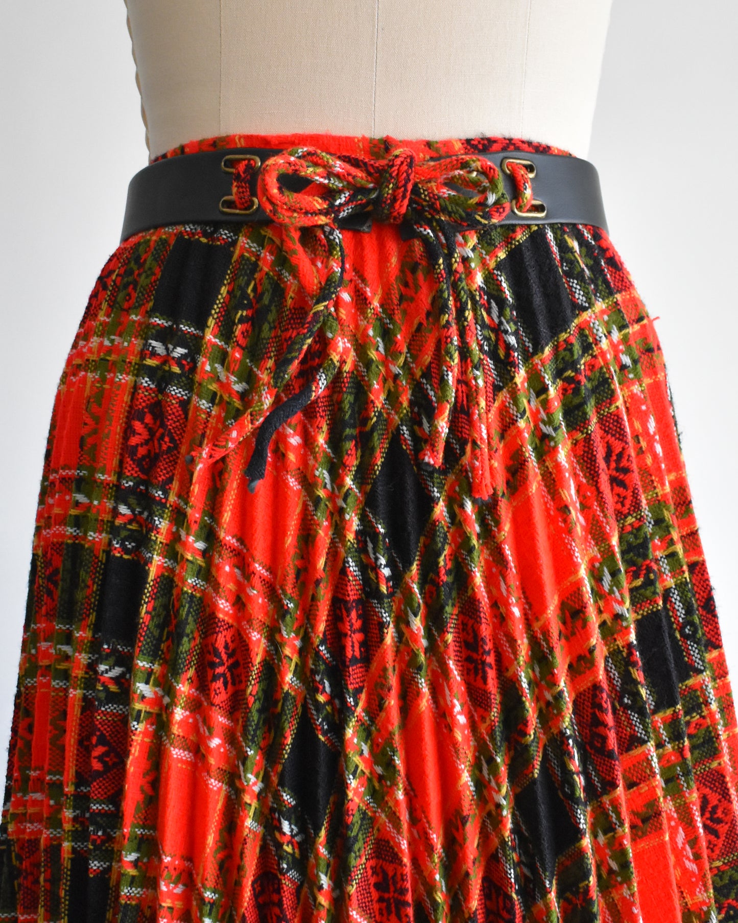 close up of the belt waistline of side front view of front view a vintage 1970s red plaid skirt on a mannequin against a white background. 