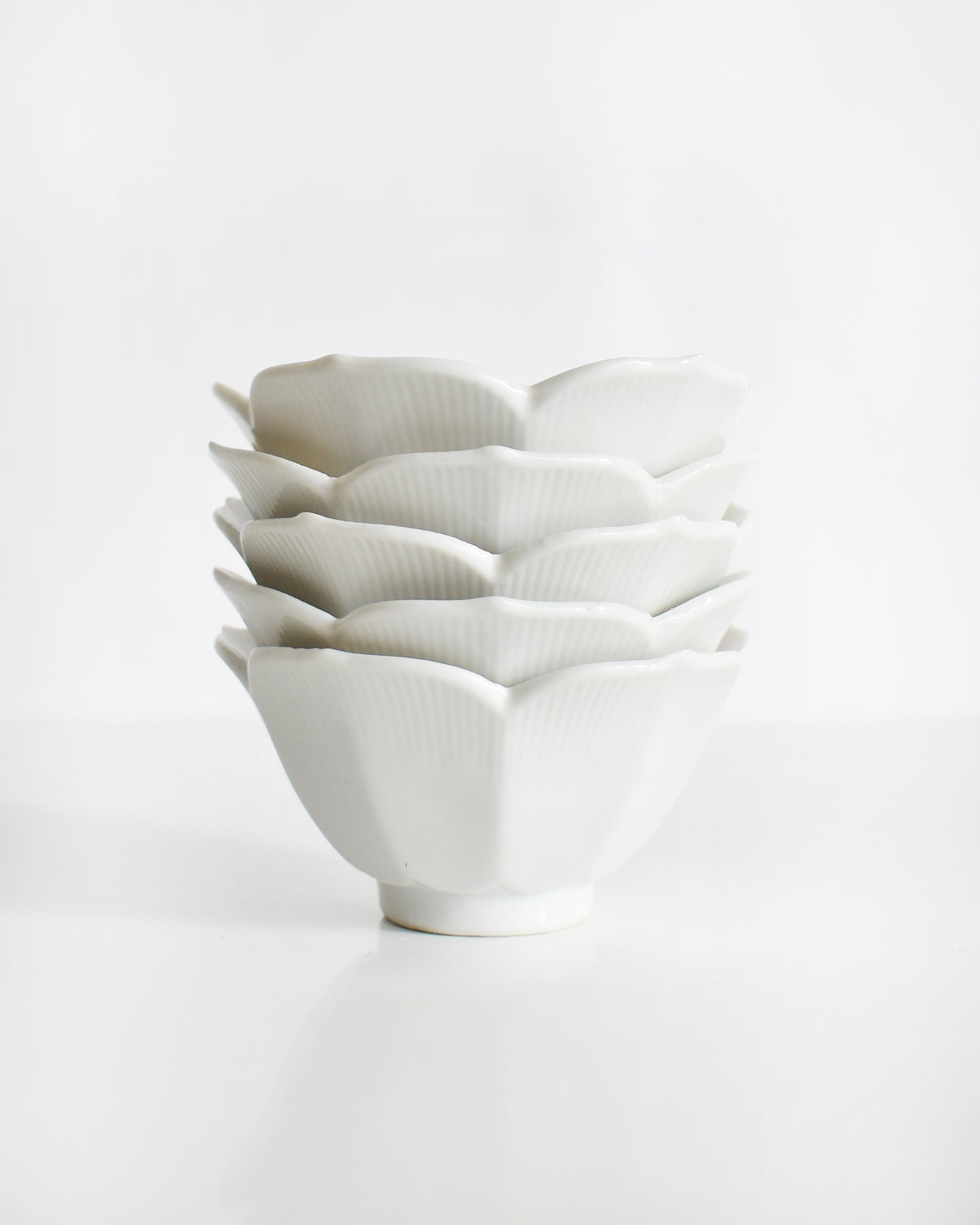 five vintage white ceramic bowls with layered petal-like lotus design on a white background
