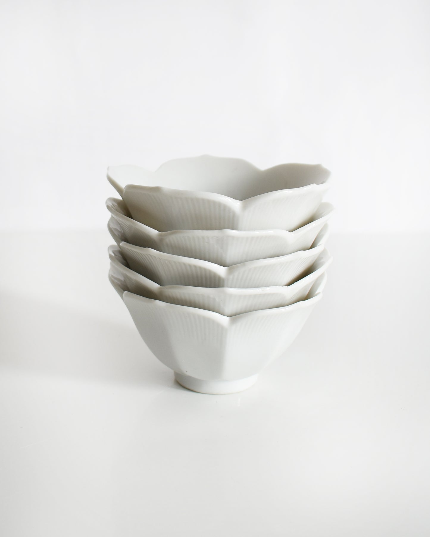Stack of white ceramic bowls on a light gray background