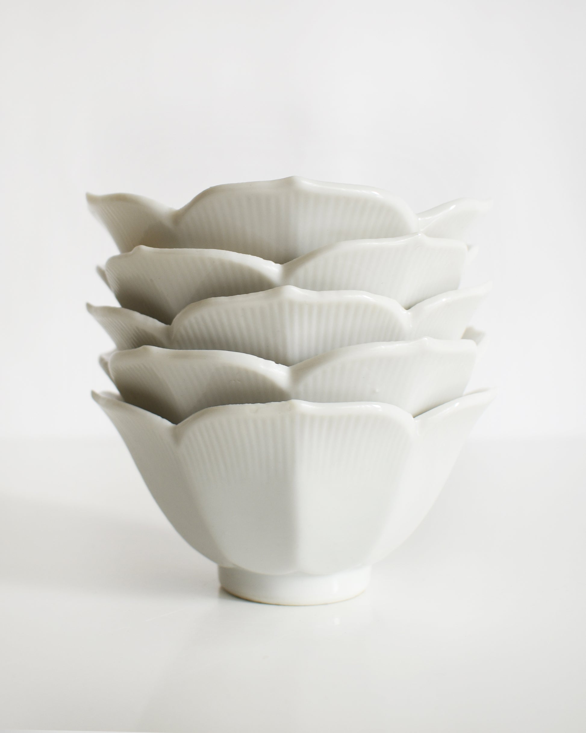 Set of white ceramic bowls with textured design on a light gray background