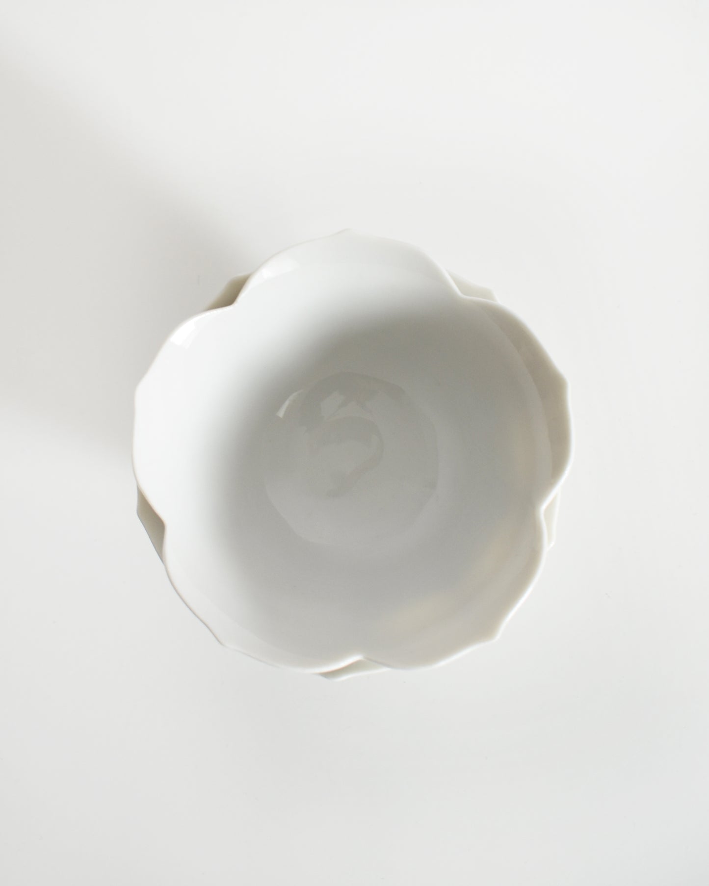 over head shot of five vintage white ceramic bowls with layered petal-like lotus design on a white background