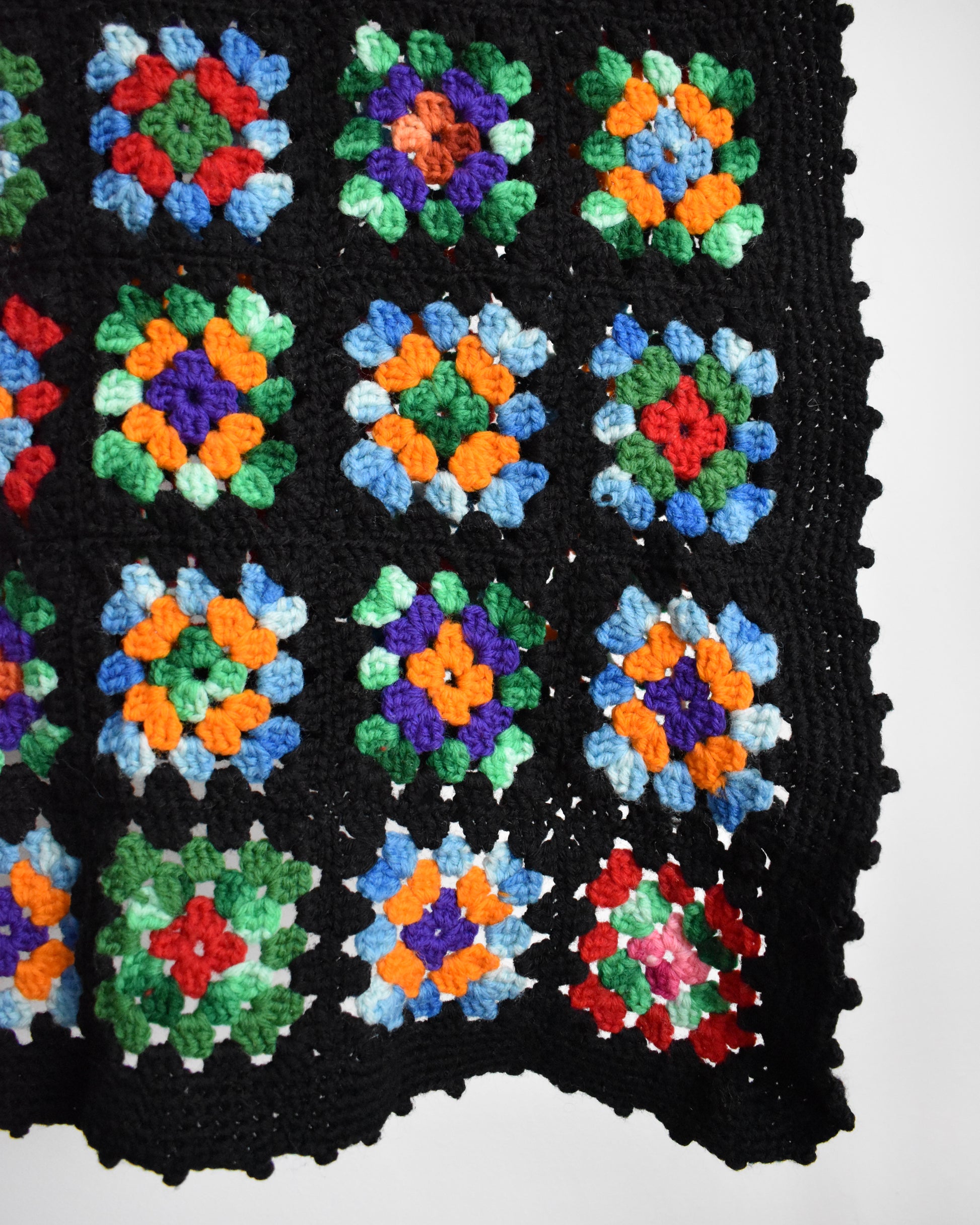 close up of a black granny square blanket with scalloped edges