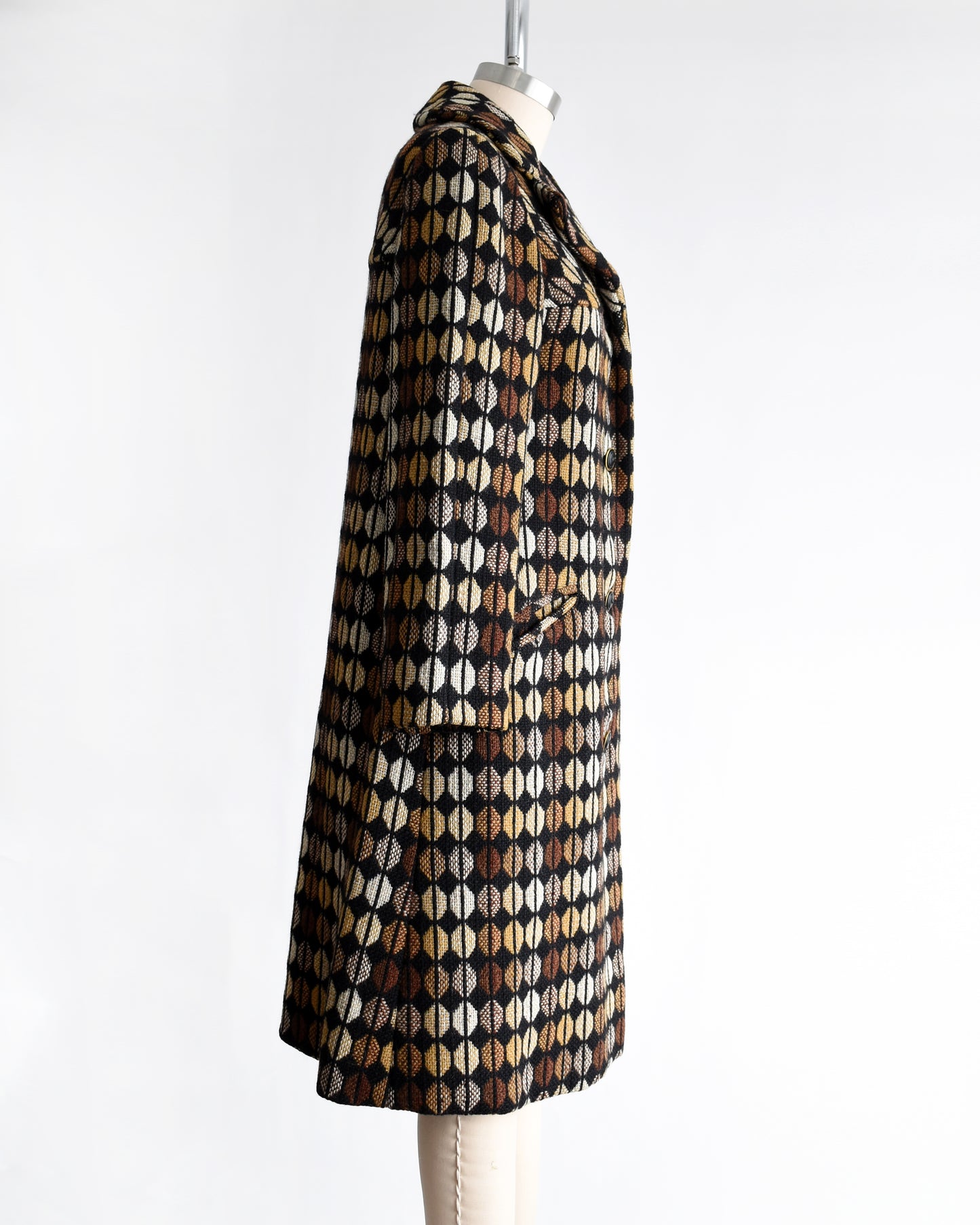 side view of a vintage 1970s black and brown patterned coat on a mannequin against a white background