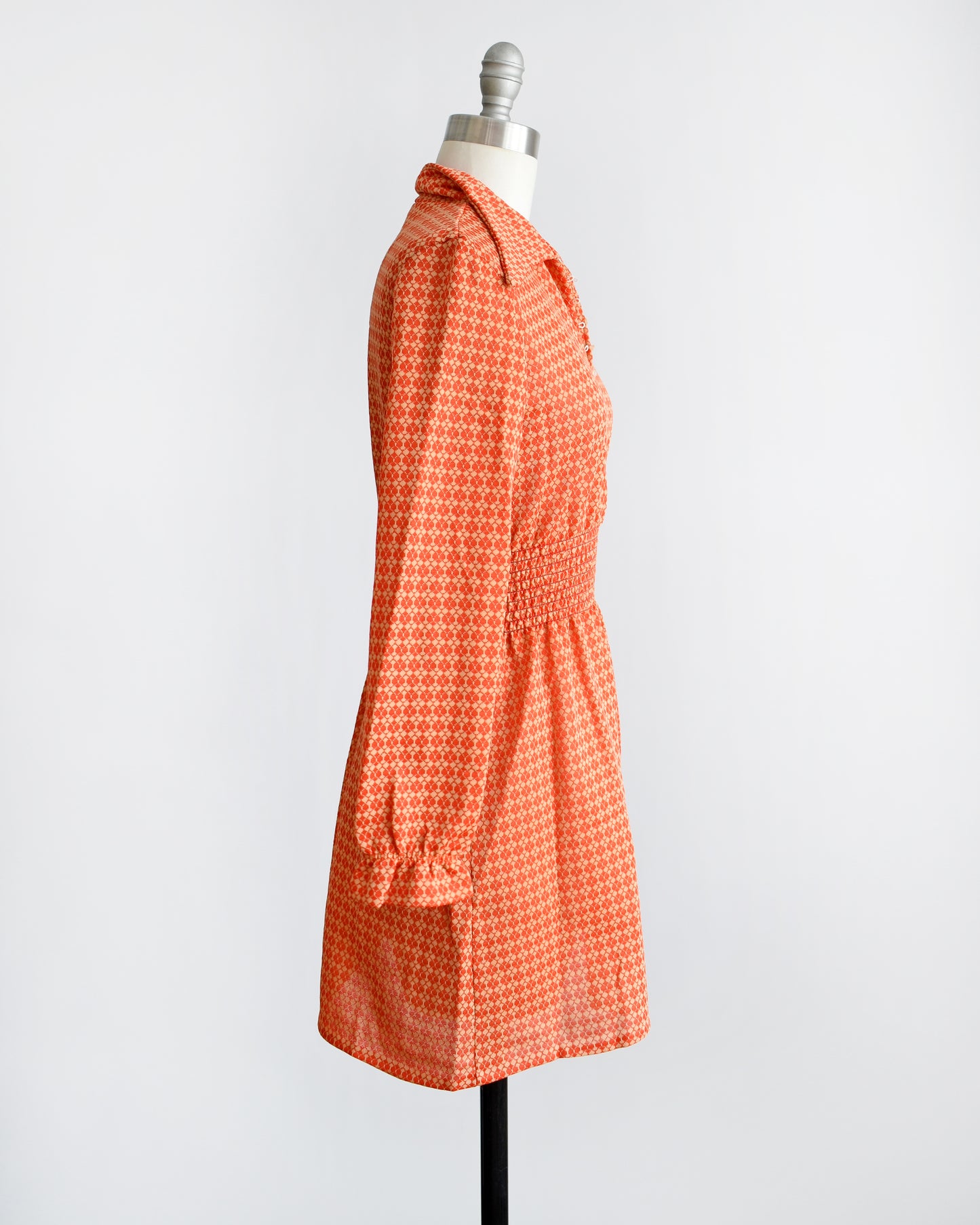 Side view of a vintage late 1960s early 1970s orange long sleeve mod mini dress with button front. 