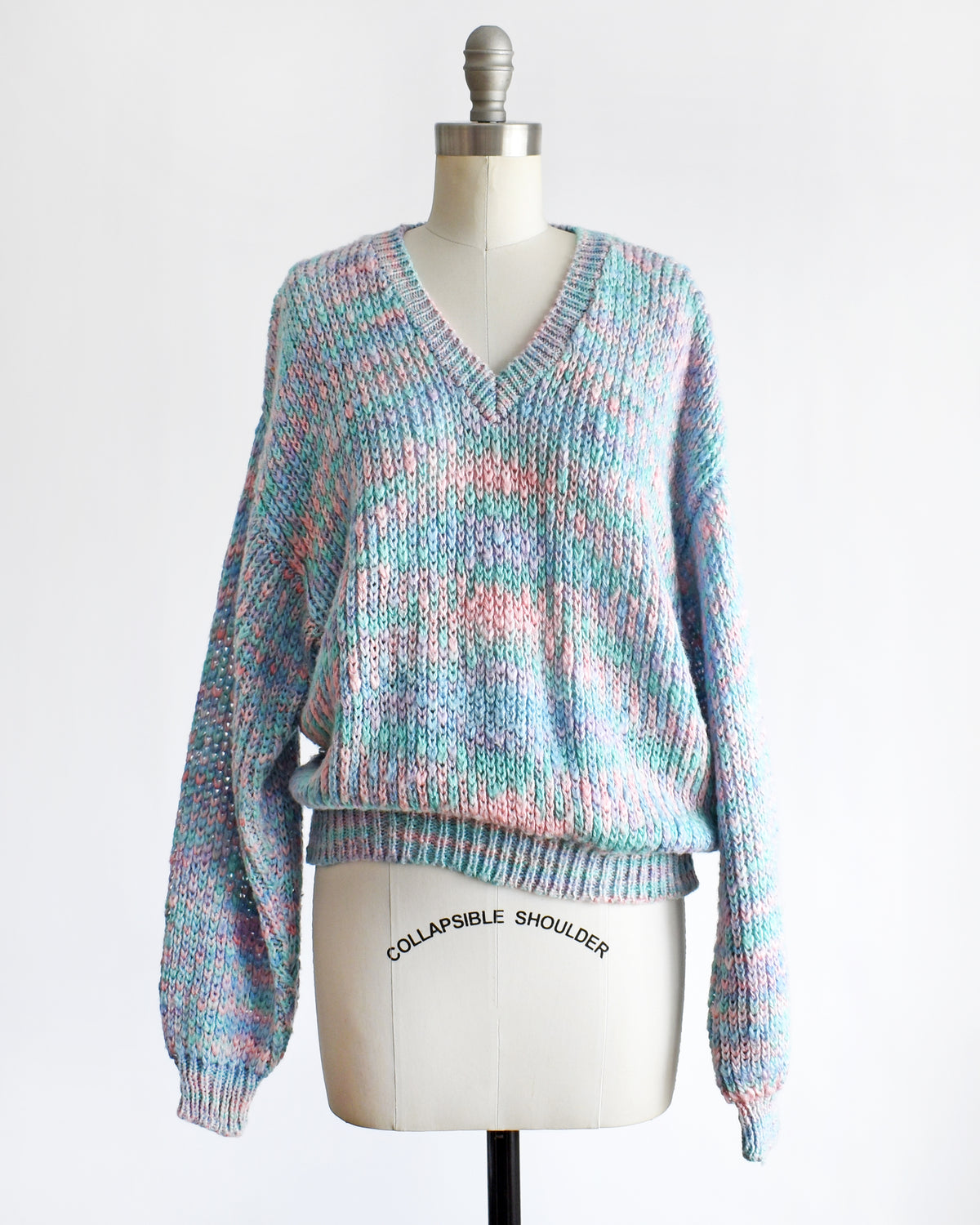 A vintage 1980s multicolor knit sweater with a V-neck and long sleeves, displayed on a cream dress form mannequin against a white background.