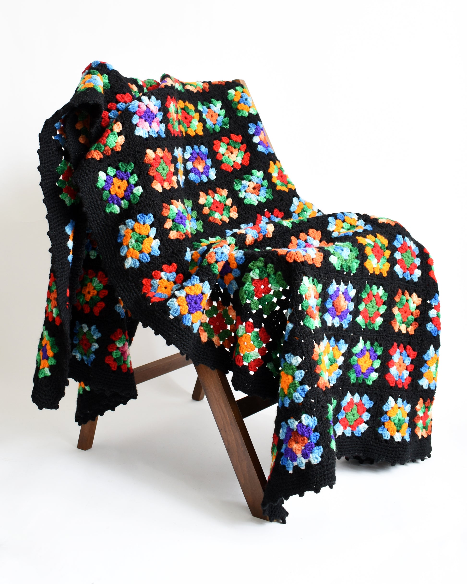 a black granny square blanket draped over a chair