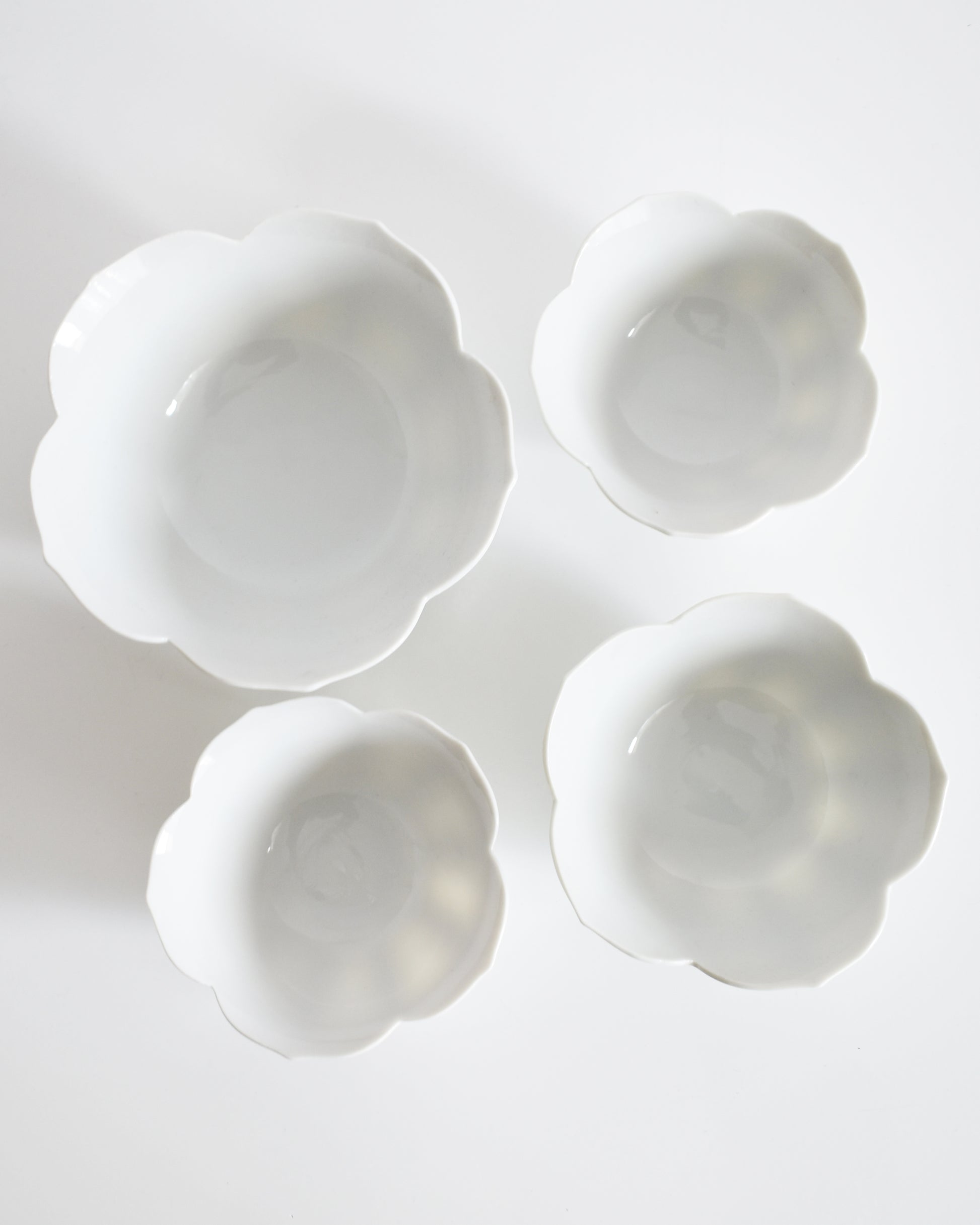 Four white ceramic bowls with floral designs on a light gray background