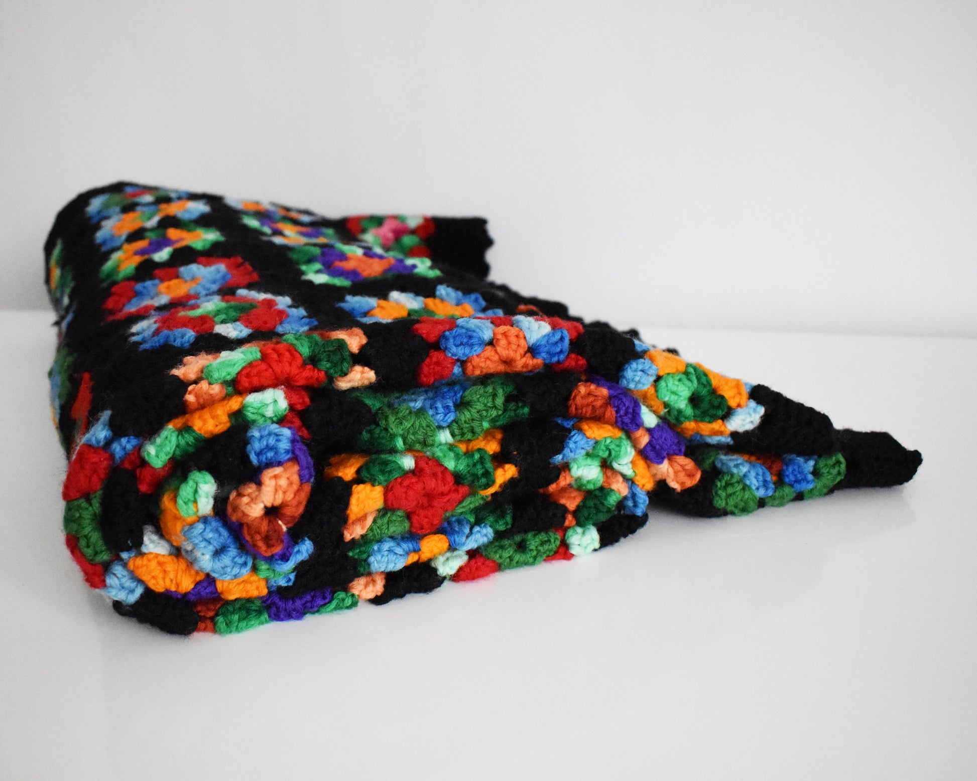 a black granny square blanket draped over a silver rod