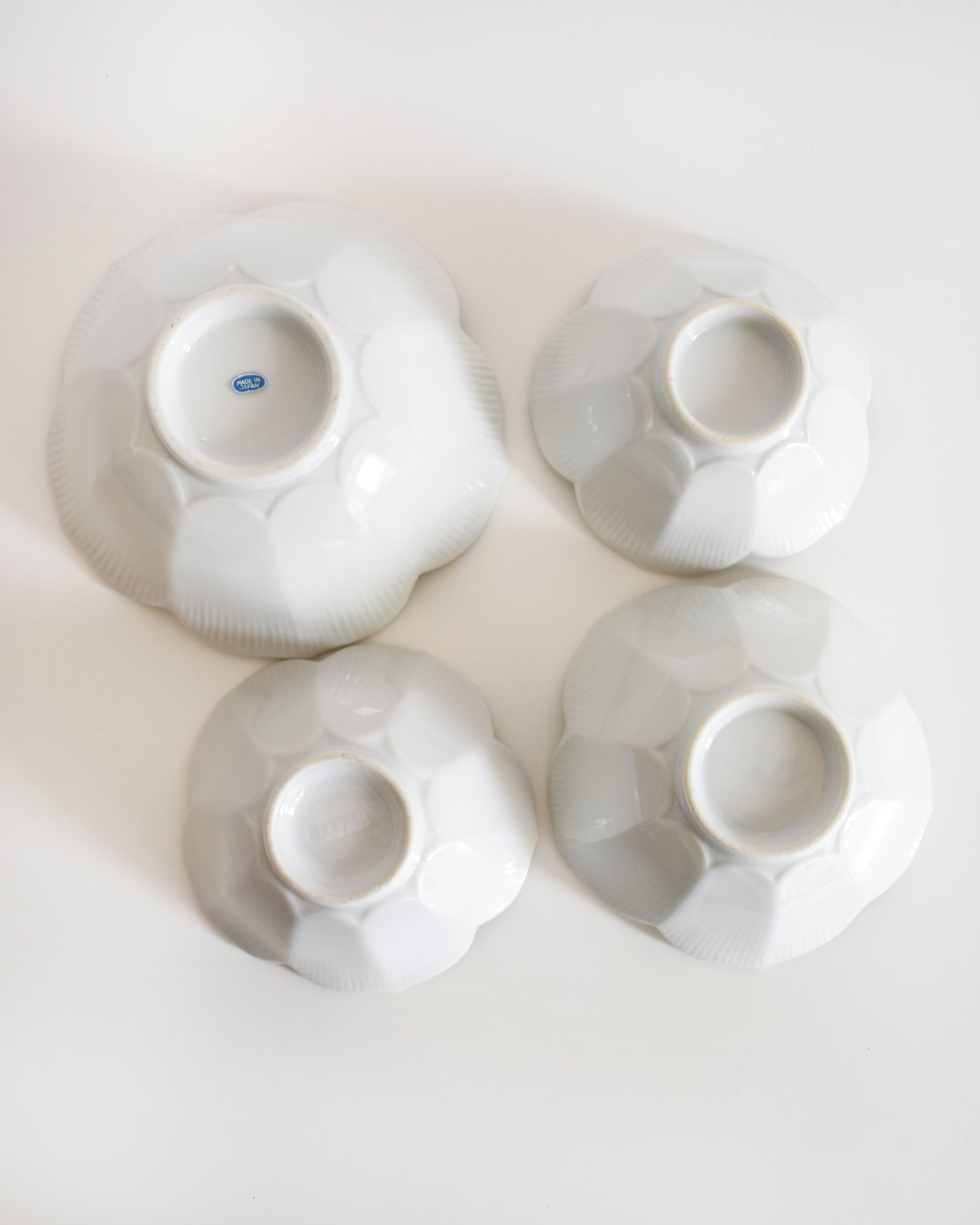 Four white ceramic bowls turned upside down on a light background