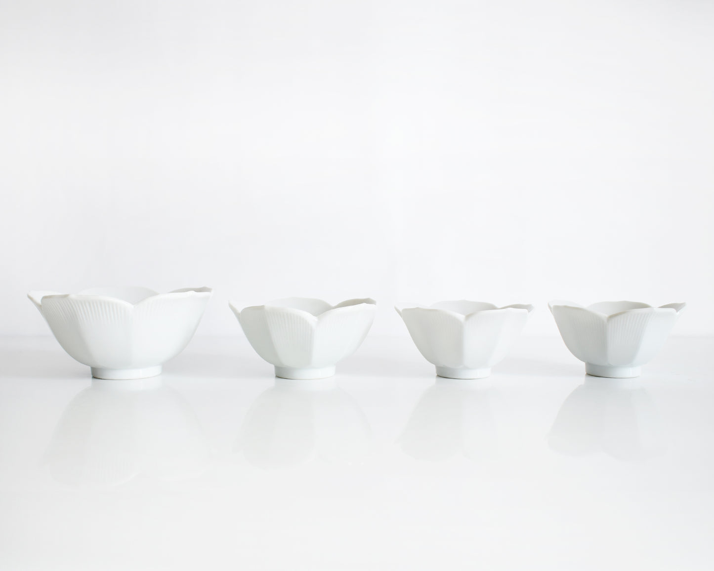 four white ceramic bowls of varying sizes on a white background
