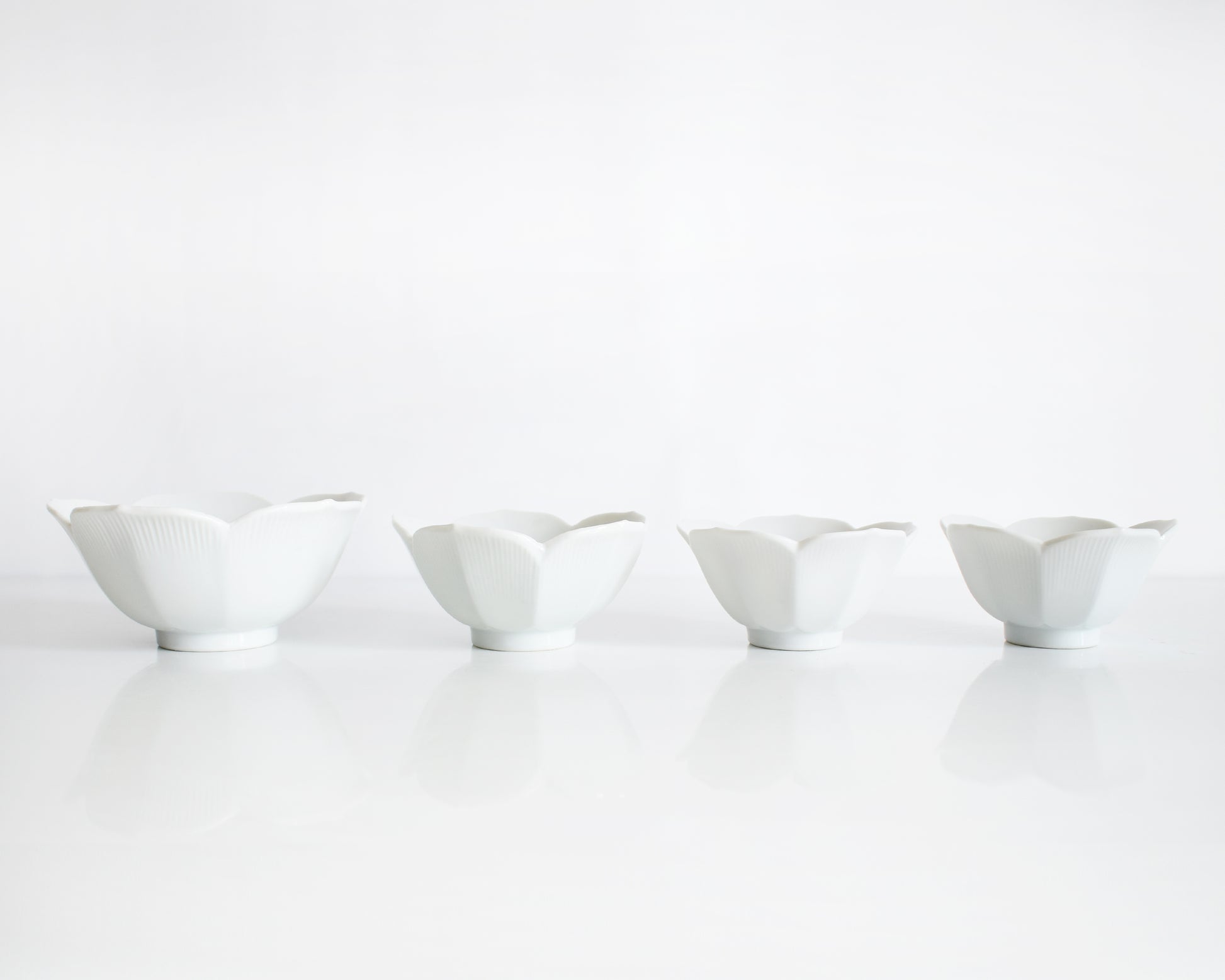 four white ceramic bowls of varying sizes on a white background