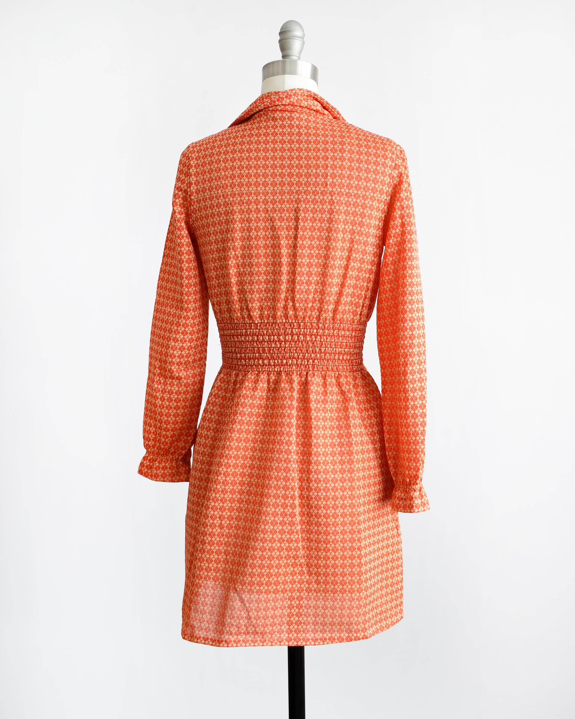 Back view of a vintage late 1960s early 1970s orange long sleeve mod mini dress with button front. 