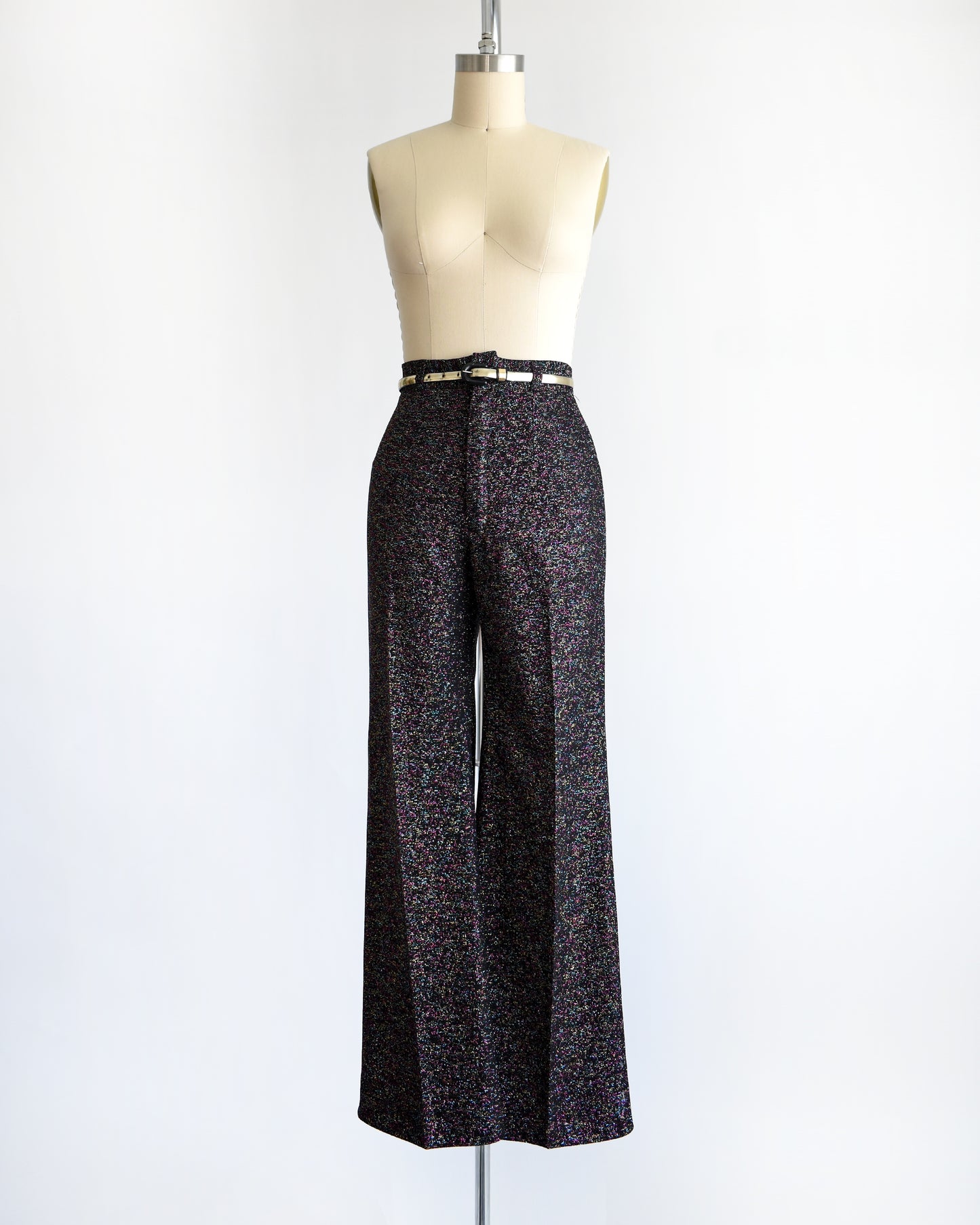 a pair of vintage 1970s black rainbow metallic pants with a silver belt on a mannequin against a white background