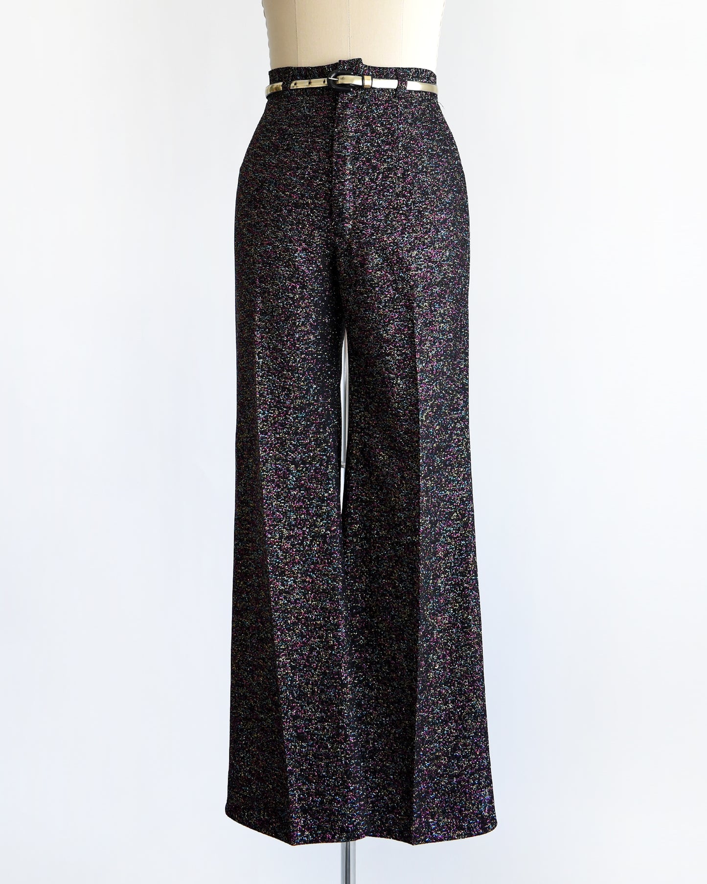 a pair of vintage 1970s black rainbow metallic pants with a silver belt on a mannequin against a white background