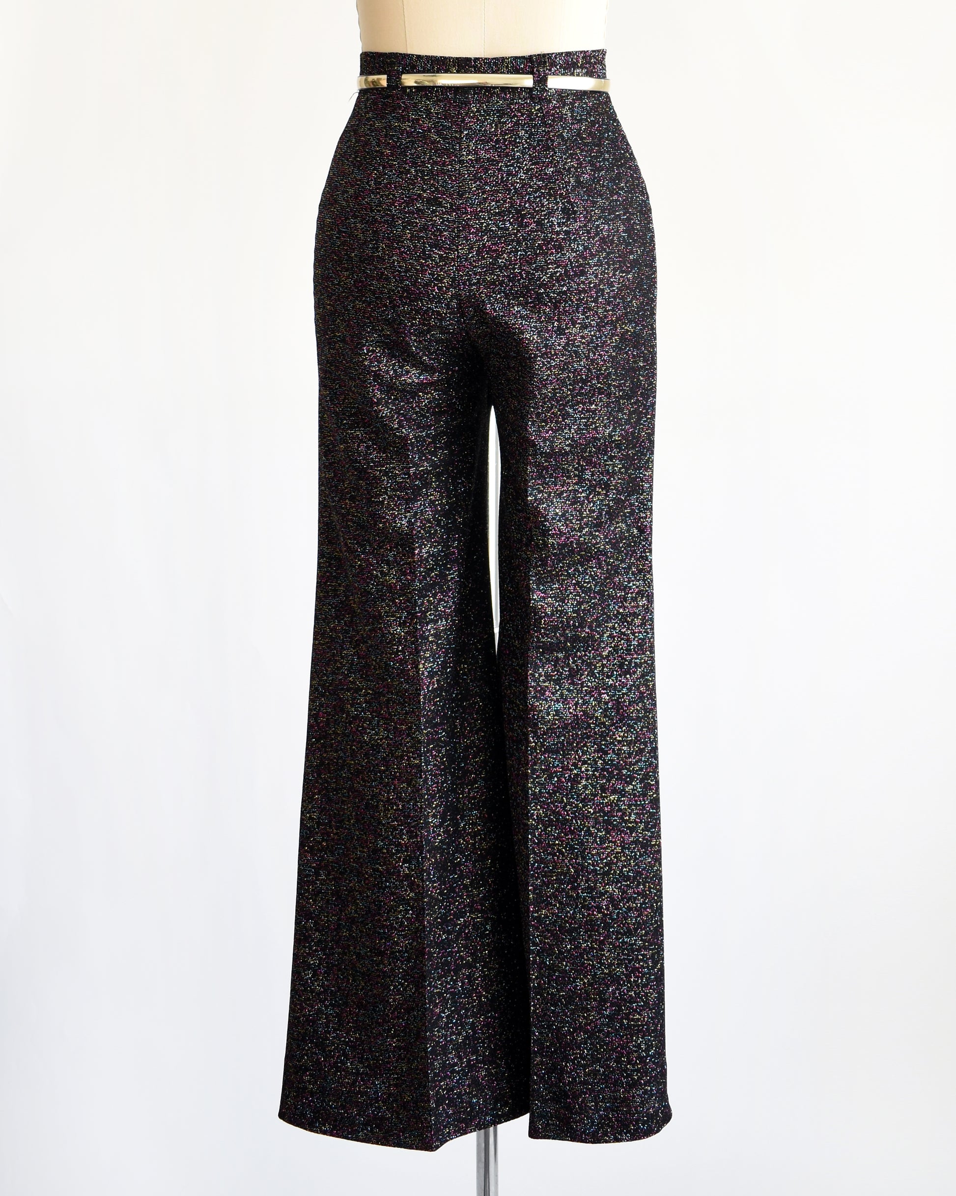 back view of a pair of vintage 1970s black rainbow metallic pants with a silver belt on a mannequin against a white background