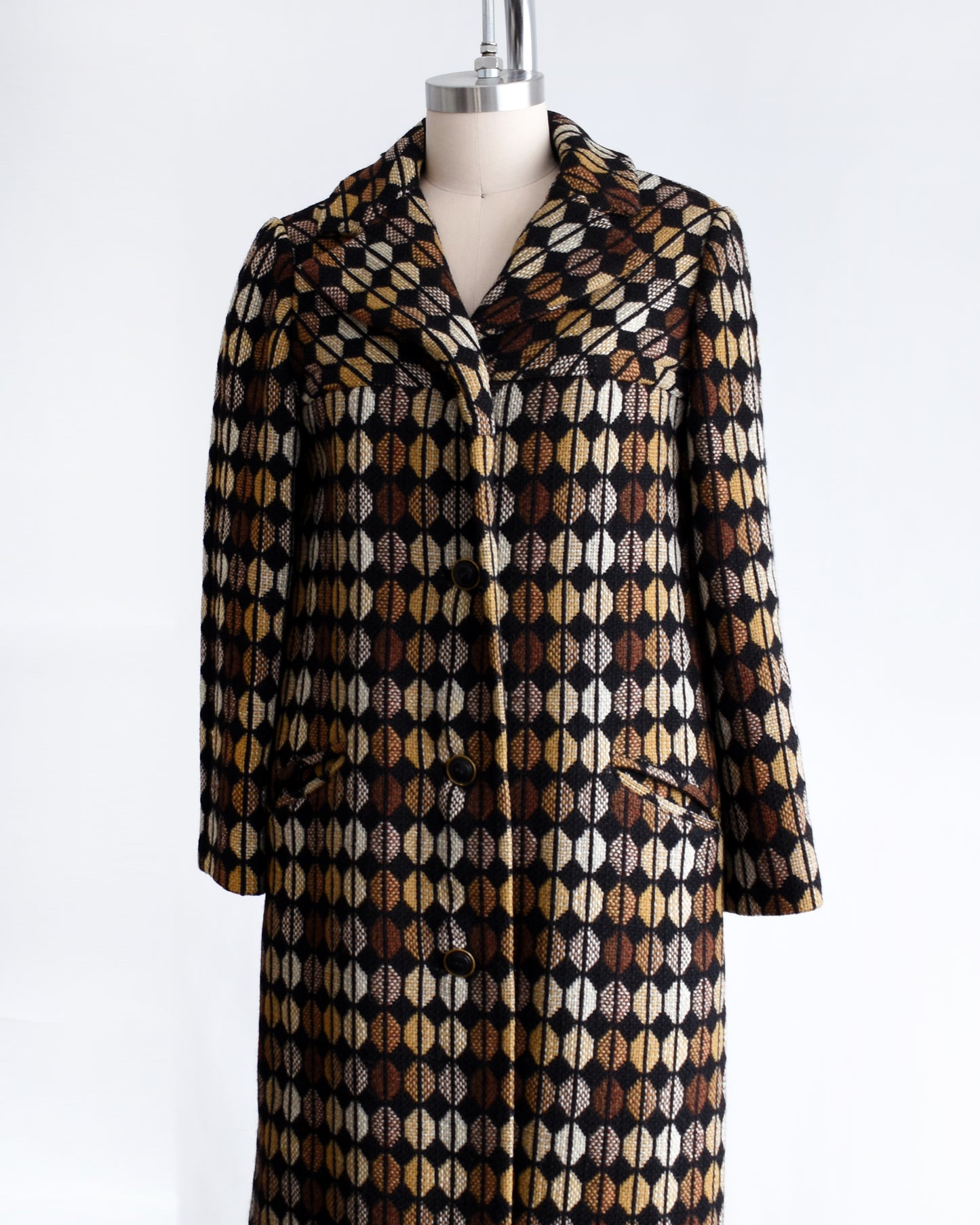 side front view of a vintage 1970s black and brown patterned coat on a mannequin against a white background