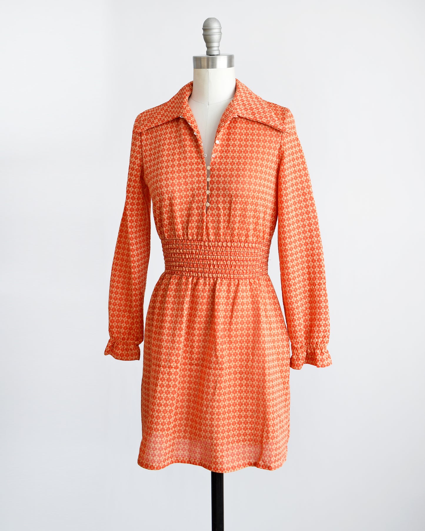 Side front view of a vintage late 1960s early 1970s orange long sleeve mod mini dress with button front. 