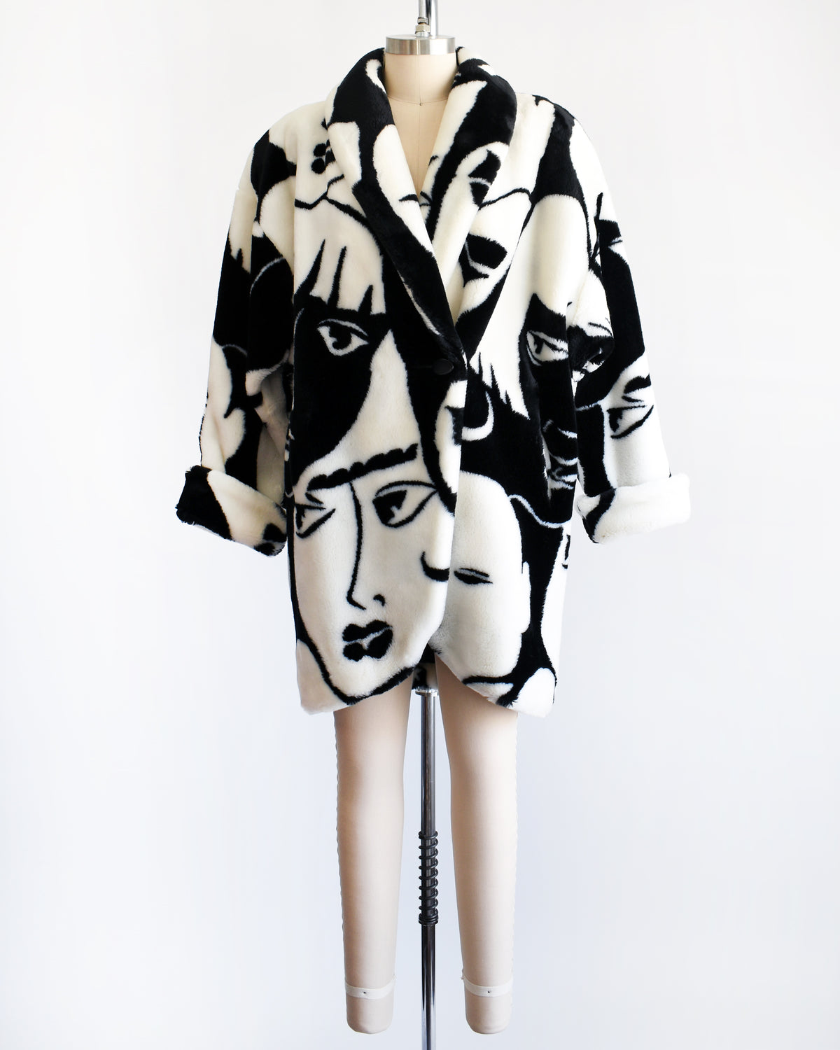 a vintage 1980s Donnybrook black and white graphic face patterned plush coat displayed on a mannequin against a plain white background.