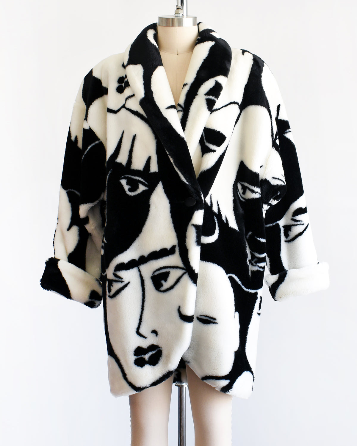 a vintage 1980s Donnybrook black and white graphic face patterned plush coat displayed on a mannequin against a plain white background.